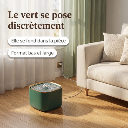 Fontaine à eau verte pour chat posée au sol dans un salon en tons crème et chêne
