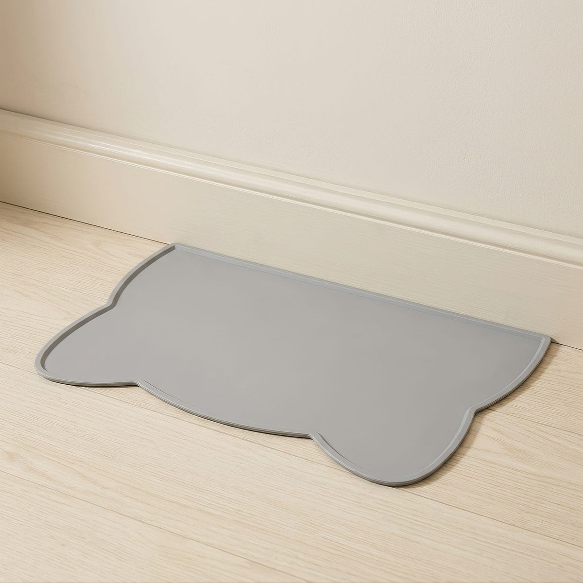 Tapis en silicone gris posé contre une plinthe sur un parquet clair