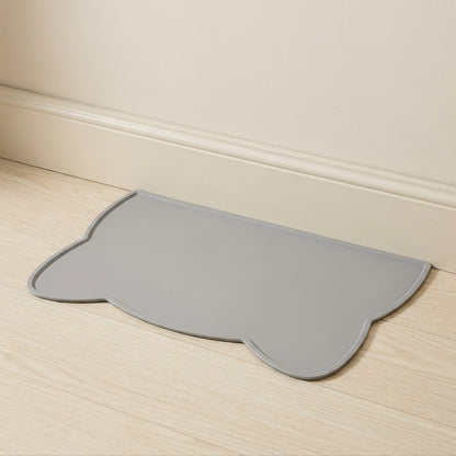 Tapis en silicone gris posé contre une plinthe sur un parquet clair
